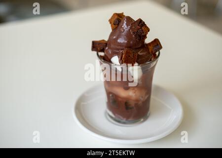 Eis mit Schokoladensirup und Brownie in einem Plastikbecher auf dem Tisch Stockfoto