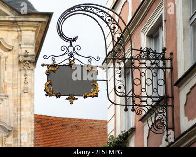 Leeres Vintage-Schild an einer Gebäudefassade aus geschmiedetem Stahl. Leerer Kopierbereich zum Einfügen eines Firmenlogos. Schild mit vielen schönen Ornamenten. Stockfoto