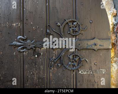Nahaufnahme einer mittelalterlichen Holztür mit geschmiedeten Stahlelementen. Das antike dekorative Design hat Ornamente und gehört zu einer alten Burg. Stockfoto