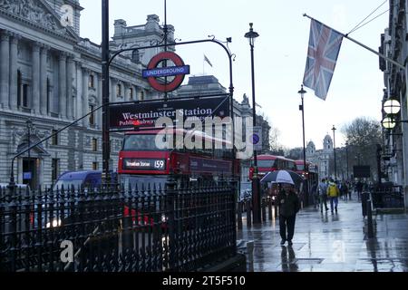London, Vereinigtes Königreich - 11. Januar 2016: Westminster Station, öffentliche U-Bahn an typisch englischem Regentag mit roten Doppeldeckerbussen und Fußgängern Stockfoto