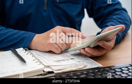 Ein Mann schreibt ein Haushaltsbuch, während er Quittungen organisiert. Eine Nahaufnahme der Hände. Steuer- oder Year-End-Abrechnungskonzept. Stockfoto