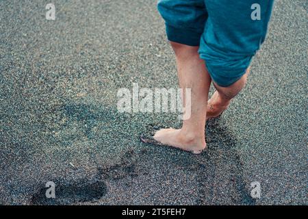 Die Füße eines Mannes stehen auf dem Sandstrand. Mit Kopierraum für Text Stockfoto