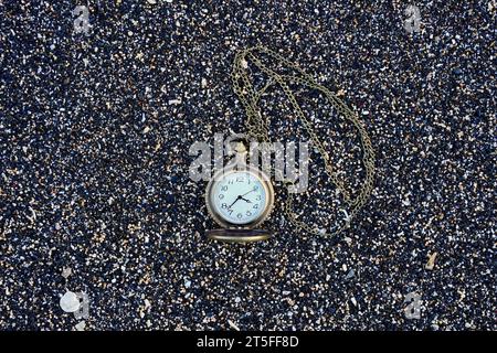 Fesselndes Bild einer goldfarbenen Taschenuhr am Strand. Mit Kopierraum für Text Stockfoto