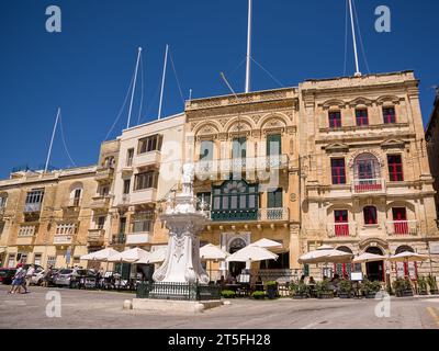 Vittoriosa, Malta - 17. Juni 2023: Sonnenschirme mit Bartischen auf dem Platz in Vittoriosa unter den Gebäuden Stockfoto