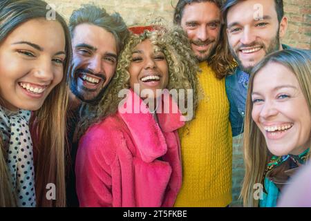 Eine bunte Gruppe von Freunden lacht und macht ein Selfie, die Freude und Freundschaft auf einer städtischen Straße ausstrahlen. Stockfoto