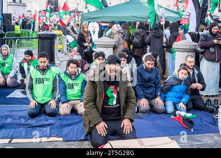 Muslimischer Mann mit einer Faust in Palästina-Flagge auf seinem Teeshirt, der ein Gebet beim pro-palästinensischen Protest auf dem Trafalgar Square, London, am 04.11.2023, führt. Stockfoto