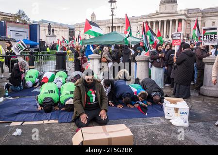 Muslimischer Mann mit einer Faust in Palästina-Flagge auf seinem Teeshirt, der ein Gebet beim pro-palästinensischen Protest auf dem Trafalgar Square, London, am 04.11.2023, führt. Stockfoto