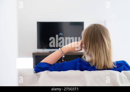 Die Frau wartet auf einen Film, der auf den Fernseher geladen wird. Langsame Internetverbindung. Stockfoto