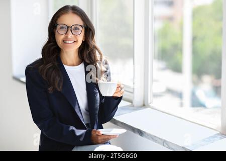 Reife Geschäftsfrau mit Brille und Kaffee im Büro Stockfoto