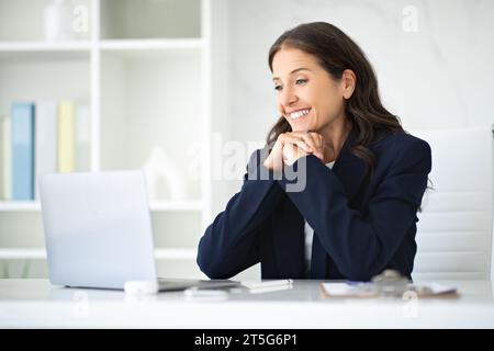 Glückliche, reife Geschäftsfrau posiert im modernen Büro Stockfoto