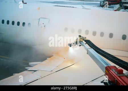 Enteisung des Flugzeugflügels vor dem Start. Winter frostige Nacht- und Bodenservice am Flughafen. Stockfoto