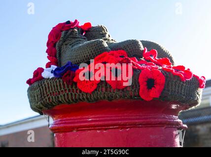 Poole, Dorset, Großbritannien. November 2023. Ein ergreifender gestrickter Briefkasten-Topper aus Soldatenstiefeln und -Hut und roten Mohnblumen in Poole, Dorset, als der Gedenktag naht und wir erinnern uns an die, die tapfer in den Kriegen gekämpft haben. - Briefkastendeckel, Briefkastendeckel, Briefkastendeckel, Topper, Garnbombardierung, Garnbombe. Quelle: Carolyn Jenkins/Alamy Live News Stockfoto