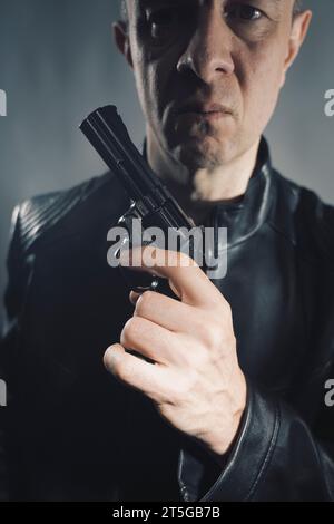 Schwarze Lederjacke Mörder Detective Spion Mörder Attentäter mit Gewehrporträt Foto. Stockfoto