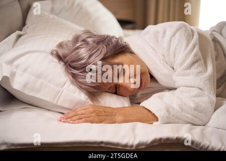 Die ältere Dame schläft in einem hellen Schlafzimmer auf weichen Kissen Stockfoto