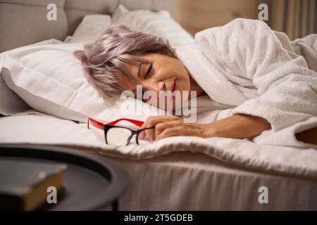 Die Frau döstet in einem hellen Schlafzimmer auf weichen Kissen Stockfoto