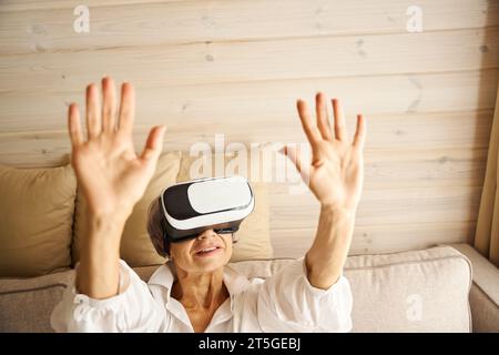 Die ältere Dame verbringt ihre Freizeit auf dem Sofa und spielt virtuelles Spiel Stockfoto