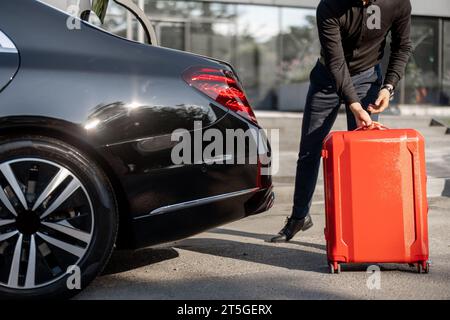 Chauffeur packt einen Koffer in ein Luxusauto Stockfoto