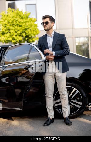 Geschäftsmann, der in der Nähe eines Luxusautos steht Stockfoto