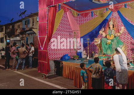 Während des Hindu-Festivals Durga Puja besuchen eine Frau und ihre Kinder einen Schrein mit einer Figur der Göttin Durga in einem Slumgebiet in Walkeshwar, Mumbai, Indien Stockfoto
