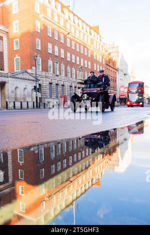 Westminster, London, Großbritannien. November 2023. Die Rennstrecke von London nach Brighton ist das am längsten laufende Motorrennen der Welt. Das erste Rennen fand 1896 statt, um die Verabschiedung des Gesetzes zu feiern, das es „leichten Lokomotiven“ ermöglichte, mit Geschwindigkeiten von mehr als 4 km/h zu fahren. Fahrzeuge, die an der Veranstaltung teilnehmen, müssen vor 1905 gebaut worden sein. Die Fahrzeuge fuhren bei Sonnenaufgang vom Hyde Park durch London, bevor sie in Richtung Süden fuhren. 1904 spiegelte sich Wolseley in der Pfütze in Whitehall Stockfoto