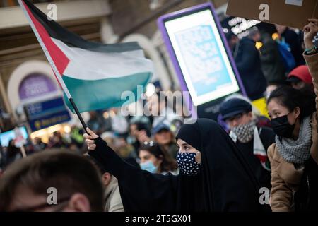 Eine Frau schwenkt während des Protestes eine palästinensische Flagge am Bahnhof Charing Cross. Tausende von Demonstranten versammelten sich in Solidarität mit dem palästinensischen Volk, während sich der Konflikt zwischen Israel und Gaza nach dem beispiellosen Angriff der Hamas Anfang Oktober weiter verschärft. Stockfoto