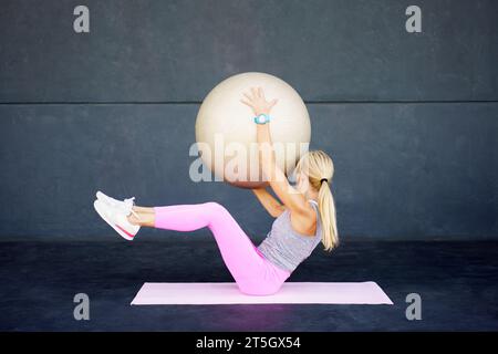 Fitte Frau, die im Club Sport mit Fitnessball macht Stockfoto