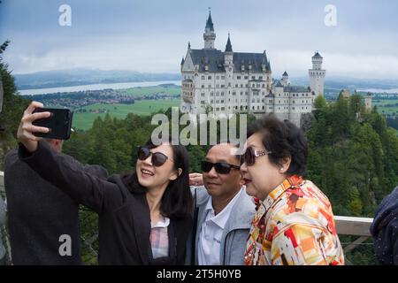 23. August 2019, Schwangau, Deutschland - glückliche asiatische Familie macht Selfies auf der Marienbrücke vor Schloss Neuschwanstein Stockfoto