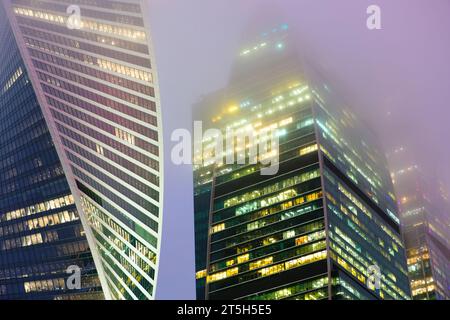 Die Spitzen moderner Firmengebäude vor dem nebeligen Himmel bei Nacht. Hochhäuser und Wolkenkratzer Moscow International Business Center.Palette Stockfoto