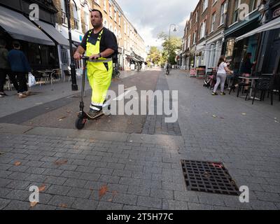 Öffentliche Plätze und Verkehrsberuhigung im Dorf Orford Road Walthamstow London, Großbritannien, mit einem Mann, der E-Scooter mit Elektroroller fährt Stockfoto