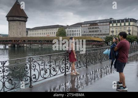 Luzern, Schweiz, 26. August 2023 - freundliches asiatisches Paar, das sich im Regen vor der Kapellbrücke fotografiert Stockfoto