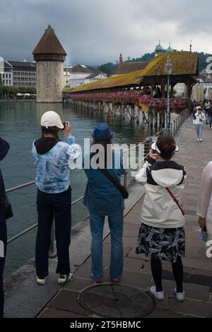 Luzern, Schweiz, 26. August 2023 - Asiatische Touristen machen Fotos und Selfies im Regen vor der Kapellbrücke Stockfoto