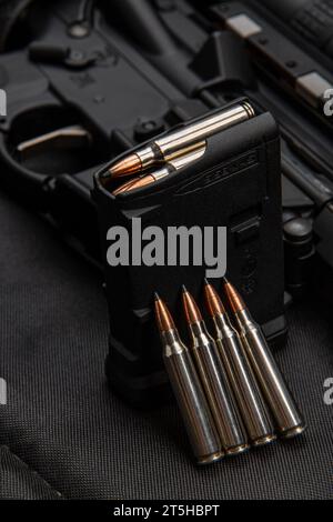 Nahaufnahme von .223 Karabinkartuschen. Geladener Waffenclip. Waffen im Hintergrund. Stockfoto