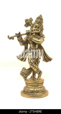 goldene Messingstatue des hindugottes krishna in ländlicher Kleidung, die Flöte auf weißem Hintergrund spielt Stockfoto