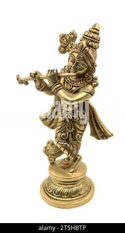 goldene Messingstatue des hindugottes krishna in ländlicher Kleidung, die Flöte auf weißem Hintergrund spielt Stockfoto