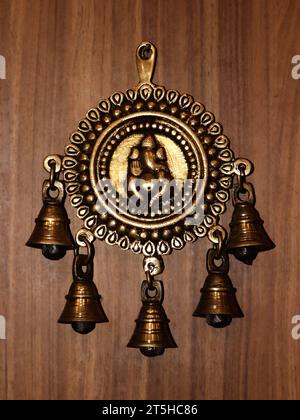 Alte antike Bronzeglocken mit einer dekorativen ganesh-Statue an einer Holzwand Stockfoto