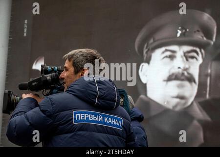 Moskau, Russland. November 2023. Ein Kameramann des Channel One Russia dreht eine Geschichte vor dem Hintergrund eines Porträts von Josef Stalin über ein Freilichtmuseum auf dem Roten Platz in Moskau; das Museum wurde anlässlich des 82. Jahrestages der historischen Parade des Roten Platzes am 7. November 1941 eröffnet, als Truppen der Roten Armee an die Front des Zweiten Weltkriegs zogen, um Moskau vor den Nazi-Truppen zu verteidigen. das Patch lautet „The Channel One“ Stockfoto