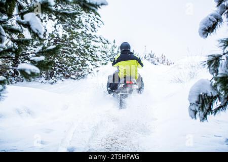 Schneemobil im Schnee. Konzept Wintersport. Der Mensch fährt mit dem Schneemobil in den Bergen. Pilot auf einem Schneemobil in einem Bergwald. Athlet reitet A Stockfoto