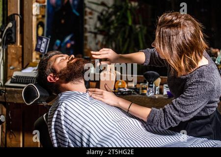 Bartmann im Friseur. Friseur, der den Kunden im Friseurladen bedient, bärtig. Friseur, Friseur. Bärtiger Mann. Friseurschere, Friseurladen Stockfoto