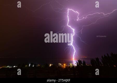 Nächtliche Blitze treffen auf den Pier am gegenüberliegenden Ufer des Flusses Stockfoto