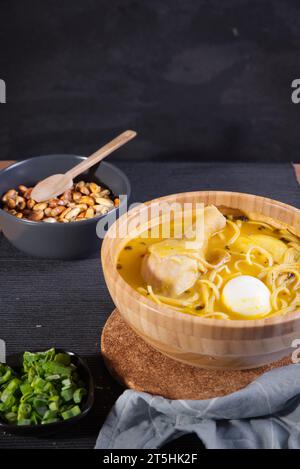 Typisches peruanisches Gericht, bekannt als Hühnersuppe, in einer Holzschale mit Zitrone und Schnittlauch. Stockfoto