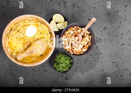 Typisches peruanisches Gericht, bekannt als Hühnersuppe, in einer Holzschale mit Zitrone und Schnittlauch. Stockfoto