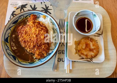 Nahaufnahme einer Schüssel mit japanischem Hühnchen-katsu-Curry, serviert mit Reis und einer Beilage mit Tempura-gebratener Süßkartoffel. Stockfoto