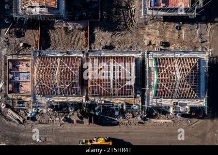 Blick aus der Vogelperspektive direkt über einer Baustelle mit neu errichteten, energieeffizienten Häusern mit freiliegenden Dachsparren und umgeben von scaf Stockfoto