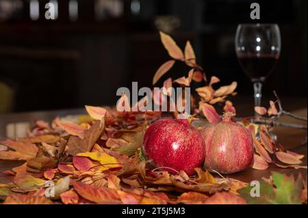 Gelbe und rote Herbstblätter auf Holzboden, Rotwein und Granatapfel im Glas. Stockfoto