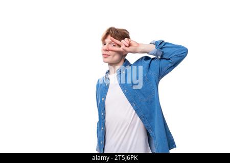 Junger kaukasischer rothaariger Mann in einem Jeanshemd über einem weißen T-Shirt, der modisch posiert Stockfoto