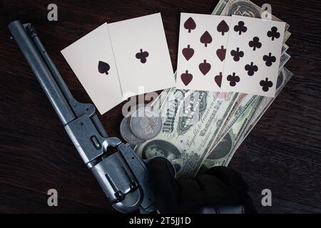 Die Hand eines Toten. Zweipaarige Pokerhand bestehend aus schwarzen Assen und schwarzen Achten und Spielerhand mit Revolverpistole. Stockfoto