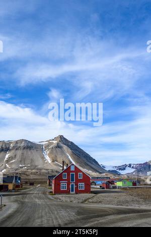 SVALBARD, NORWEGEN – 17. JULI 2023: Stadt NY Alesund, farbenfrohe Gebäude und Forschungsstationen auf der Hauptstraße mit verschneiten Bergen im Hintergrund Stockfoto