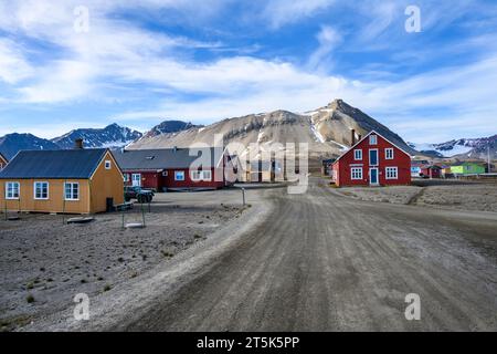 SVALBARD, NORWEGEN – 17. JULI 2023: Stadt NY Alesund, farbenfrohe Gebäude und Forschungsstationen auf der Hauptstraße mit verschneiten Bergen im Hintergrund Stockfoto