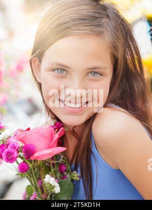 Das bezaubernde Happy Young Blue Eyed Girl hält einen frisch geschnittenen Blumenstrauß auf dem Bauernmarkt. Stockfoto