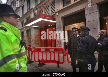 Polizisten wachen, während ein Aktivist das Baldachin über dem Haupteingang besetzt. Aktivisten der Palästinensischen Aktion besetzen und zielen den italienischen Rüstungsgiganten Leonardo in ihrem Londoner Hauptquartier und schließen sie ab. Leonardo beliefert Israel mit Kampfjets und Waffen, die derzeit im Gazastreifen eingesetzt werden. Die Palästinensische Aktion verlangt, dass Waffenunternehmen, die Waffen für Israel bereitstellen, dauerhaft stillgelegt werden. Sie haben angekündigt, dass Unternehmen, die Waffen an die israelischen Streitkräfte verkaufen, und ihre Partnerunternehmen mit direkten Maßnahmen ins Visier genommen werden. Mit diesen Aktionen sollen die hervorgehoben werden Stockfoto